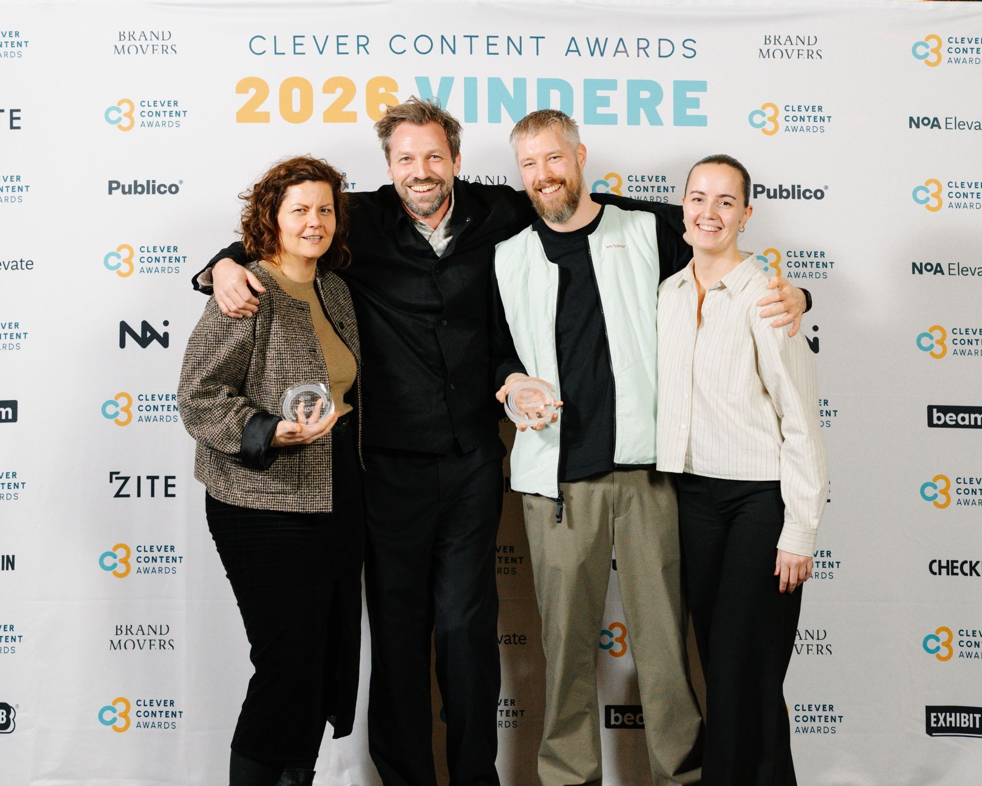 Lars Østergaard og kolleger med priserne foran væggen med Clever Content Awards-vindere